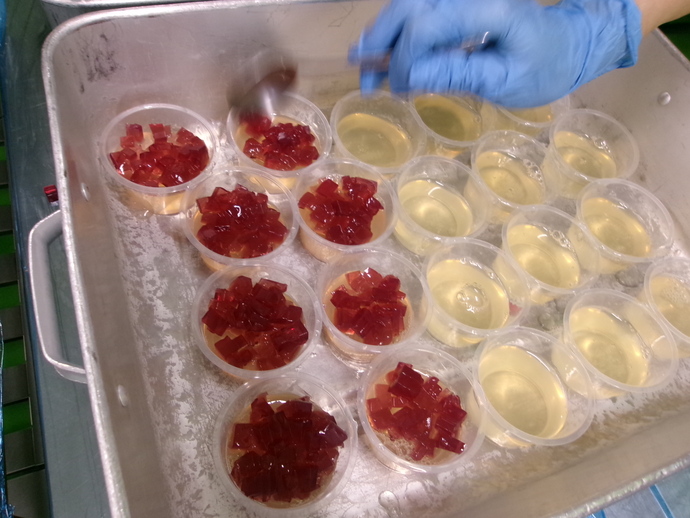 花びらのように細かく切った赤のぶどうジュースの寒天を白のぶどうジュースの寒天の上にのせている様子